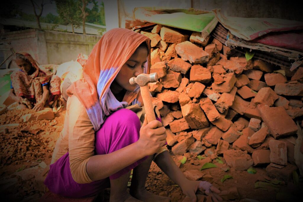 Bangladeshilainen tyttö lyö tiiliskivejä vasaralla.