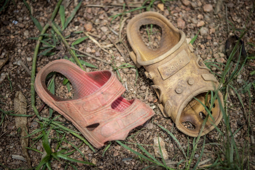 Rikkoutuneet muoviset sandaalit hiekassa Ruandassa.
