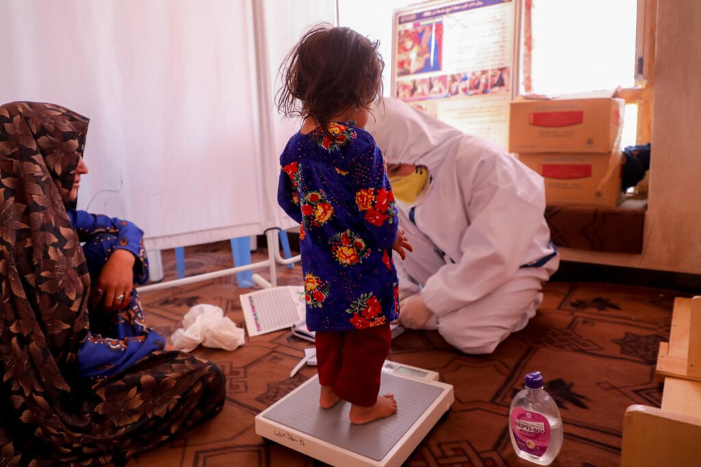 Afganistainen lapsi punnitaan terveystarkastuksessa.