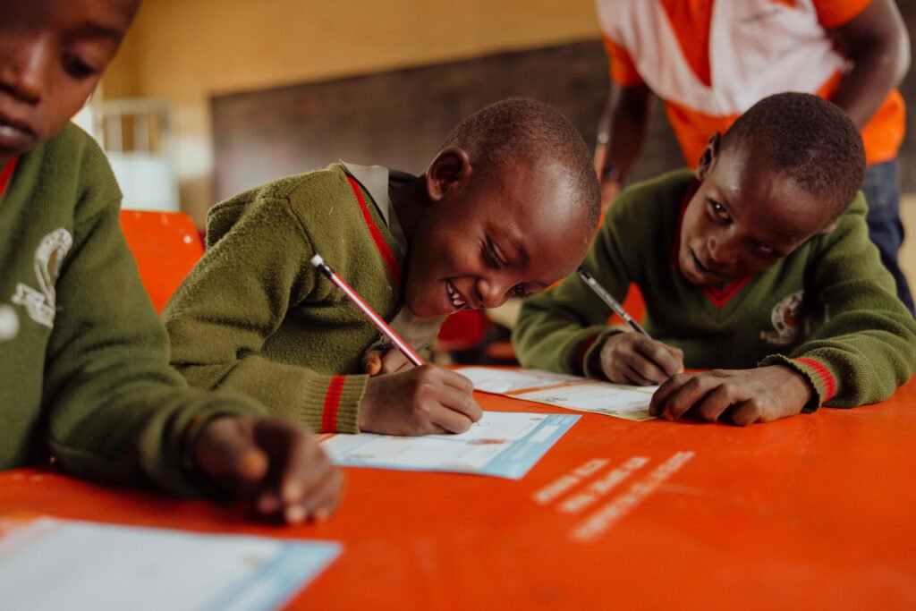 Kenialainen koulupoika kirjoittamassa kirjeen kummilleen.