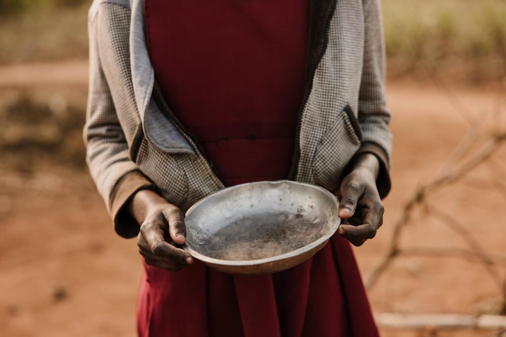 Malawilainen tyttö pitämässä tyhjää ruokalautasta.
