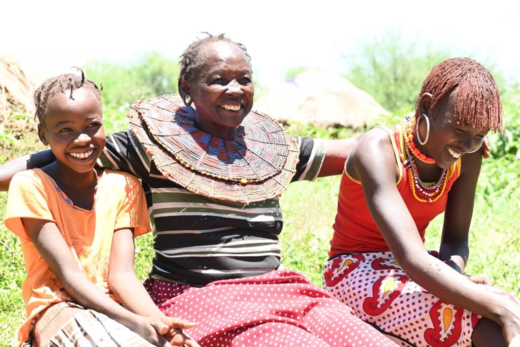Kenialainen äiti ja kaksi tytärtä nauramassa yhdessä.