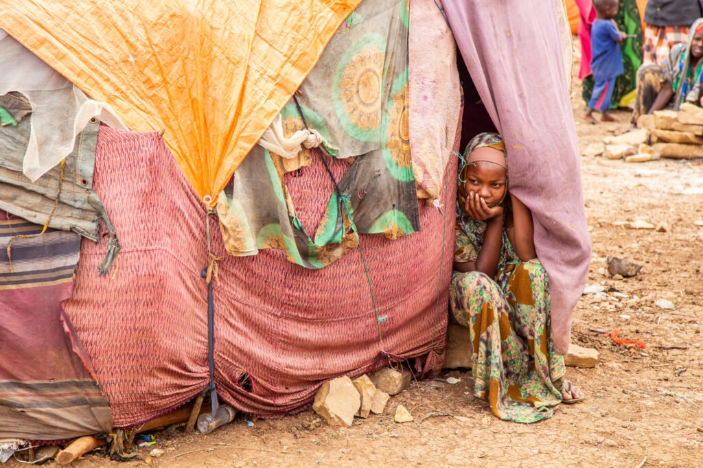 Somalilainen tyttö istuu pakolaisleirn teltassa katsomassa ulos.