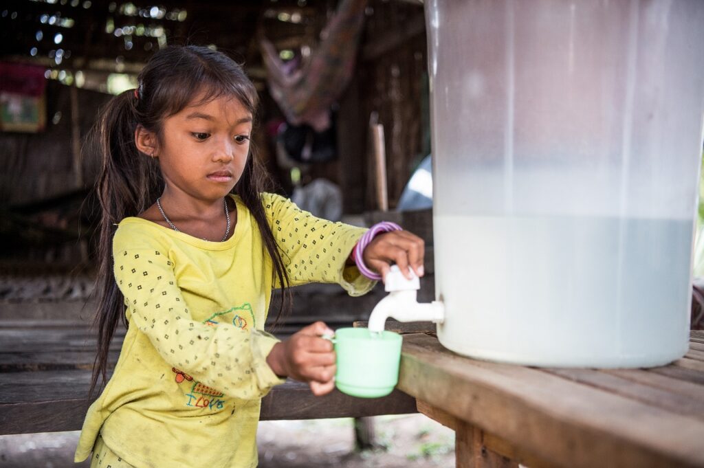 Kambodzalainen tyttö hakee vettä mukiin kanisterista.