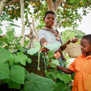 Kenialainen äiti ja lapsi tutkivat puutarhansa kasvien lehtejä.