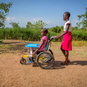 Kenialainen tyttö työntämässä pikkusiskoaan pyörätuolissa.