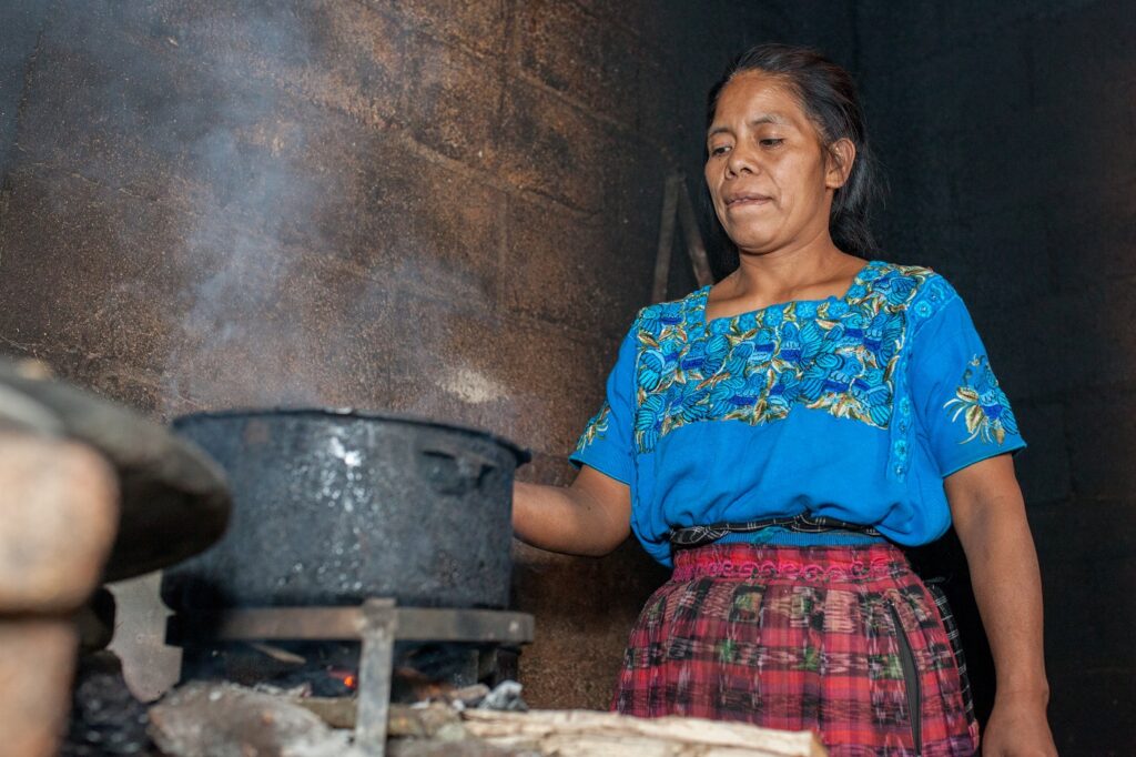 Perulainen nainen keittämässä ruokaa liedellä.