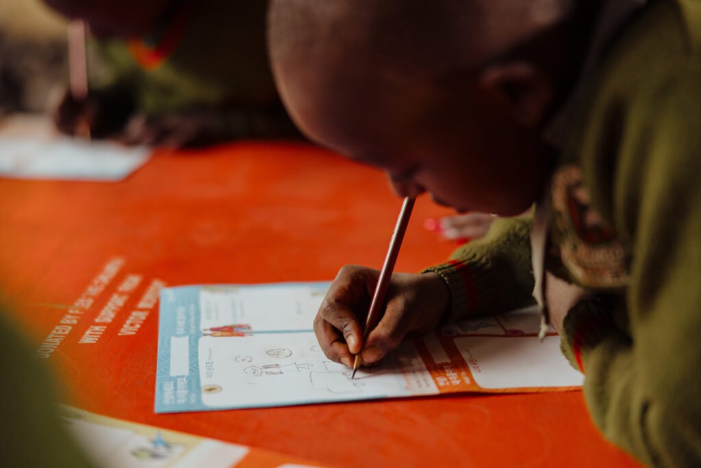 Kenialainen koulupoika kirjoittamassa kirjeen kummilleen.