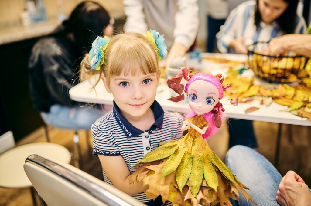 Ukrainalainen tyttö esittelee Kiovassa työpajassa tekemäänsä nuken mekkoa.