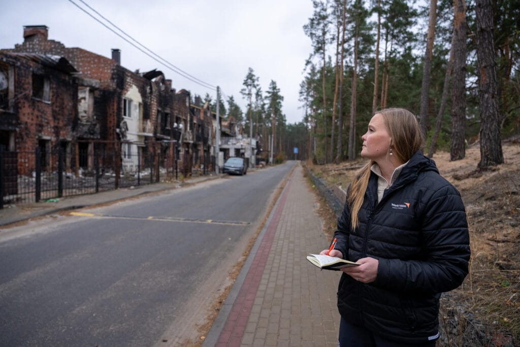 Suomen World Visionin toiminnanjohtaja Annette Gothóni ilmahyökkäyksissä tuhoutuneiden talojen edessä.